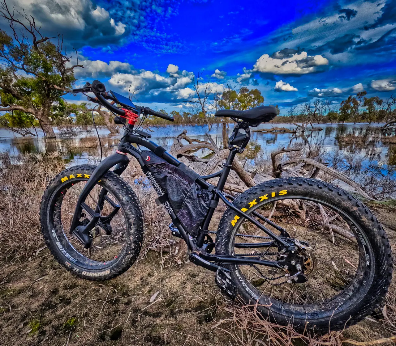 Black fat bike beside a flooded lake under a big blue sky