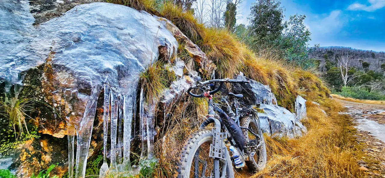 Fat bike beside a rock wall hung with icicles