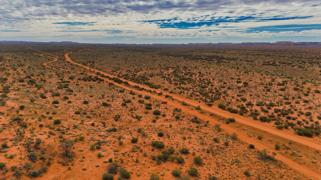 Aerial view of a red sand track running through desert scrub