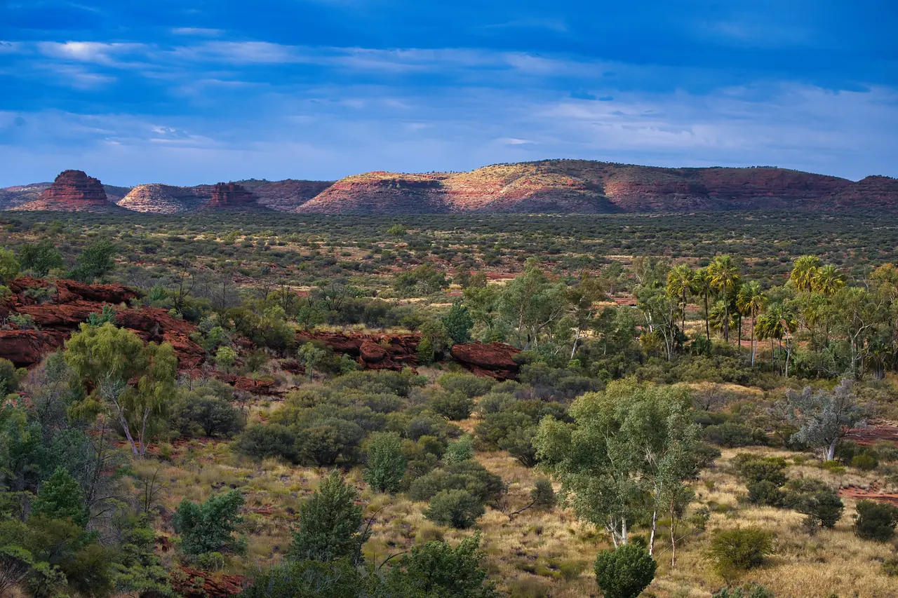 Red ranges and green scrub under a blue sky